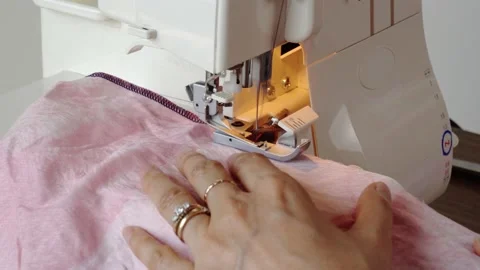 Serger Overlock sewing machine closeup. Seamstress sewing edge on fabric. Stock Footage 138784851
