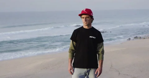 Sergio Cosme standing on sandy beach with ocean and looking in distance Stock Footage 156282898