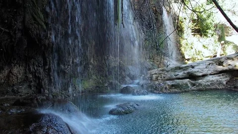 A series of small waterfalls flows down the mountain into a turquoise mountain Stock Footage 247186201