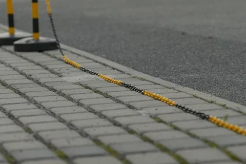 Series of upright posts linked by chain creating clear pavement border Foto stock
