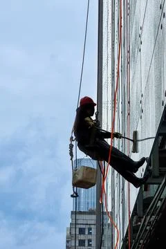 Series of worker cleaning window of high rise building with water from hose Stock Photos