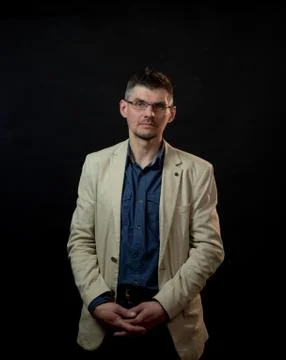 Serious actor in jacket and glasses stands crossing hands Stock Photos