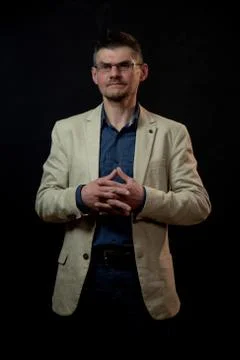 Serious actor in jacket poses twisting fingers in studio Stock Photos
