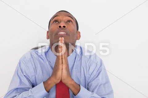 Serious Afro businessman looking up with joined hands Stock Photos