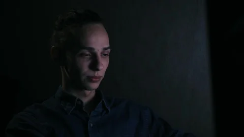Serious and pensive man talking with people via computer in late night at home Vidéo 99051222