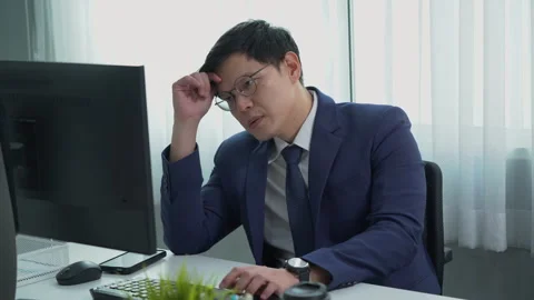 Serious asian business man using computer on desk in office Stock Footage 252822686