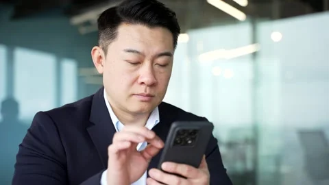 Serious asian businessman is using browsing mobile phone at workplace in busines Stock Footage 310688006