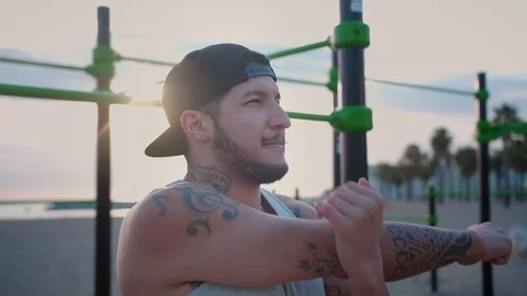Serious athletic Hispanic guy stretching at summer morning time on the beach Video stock 108442248