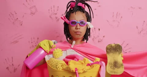Serious attentive dark skinned young woman holds dirty sponge and spray Stock Footage 154733681