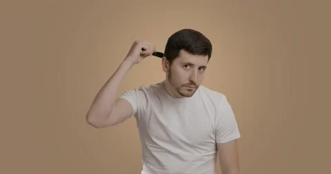Serious bearded man looking at the camera and combing his hair with a hairbrush Stock Footage 226417285