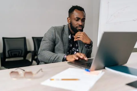 Serious black male programmer developer coding software on laptop computer Foto stock