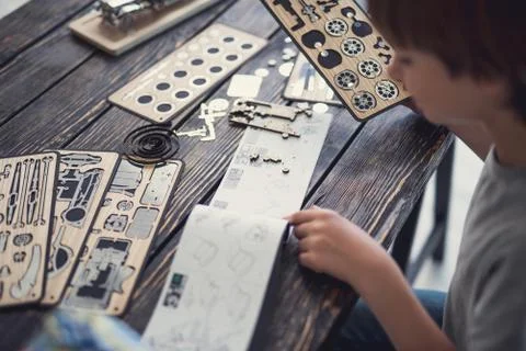 Serious boy checking the instructions while working with wooden constructor Stock Photos