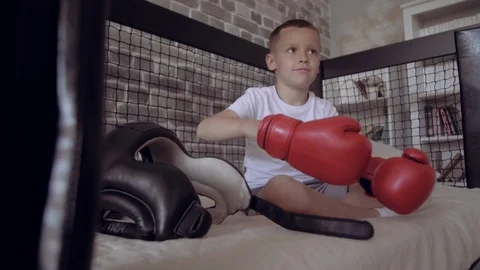 Serious boy in red Boxing Gloves and black Head guard swining with hands in his Stock Footage 111554867
