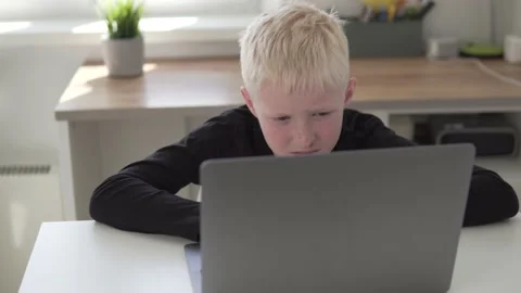 Serious boy schoolboy blond engaged at home at the computer Stock Footage 154935814