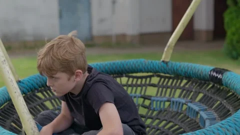 The Serious Boy is Swinging on a Swing Slow Motion Stock Footage 345710626