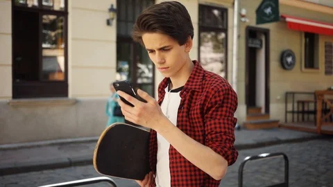 Serious boy using a mobile phone walk keeps skate guy business fashion hand Video stock 92050857