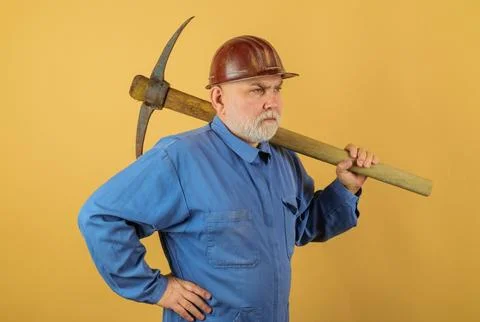 Serious bricklayer in hard hat with pickaxe. Bearded construction worker in.. Stock Photos