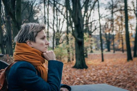 Serious brooding short-haired blonde in coat and scarf in autumn Stock Photos