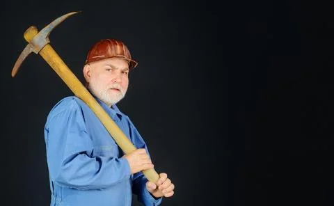 Serious builder in uniform with pickaxe on shoulder. Coal miner with pickax.  Stock Photos