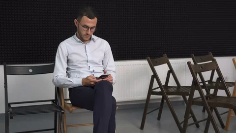 Serious business man in empty conference room touching smartphone Stock Footage 77293941