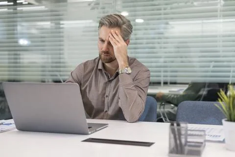 Serious business man working on documents looking concentrated with laptop on Stock Photos