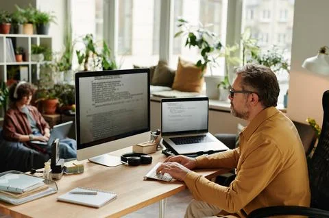Serious businessman concentrating on decoding data by workplace Stock Photos