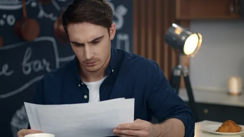 Serious businessman learning financial data at home office. Guy looking papers Stock Footage 130083435