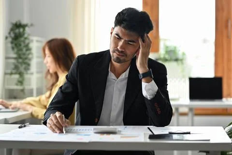 Serious businessman reading document, solving business problem. Emotional Stock Photos