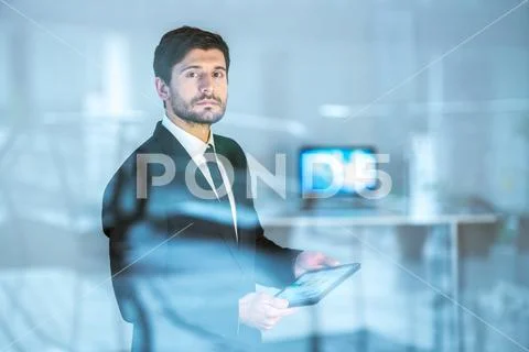 The serious businessman stand with a tablet over the window Stock Photos