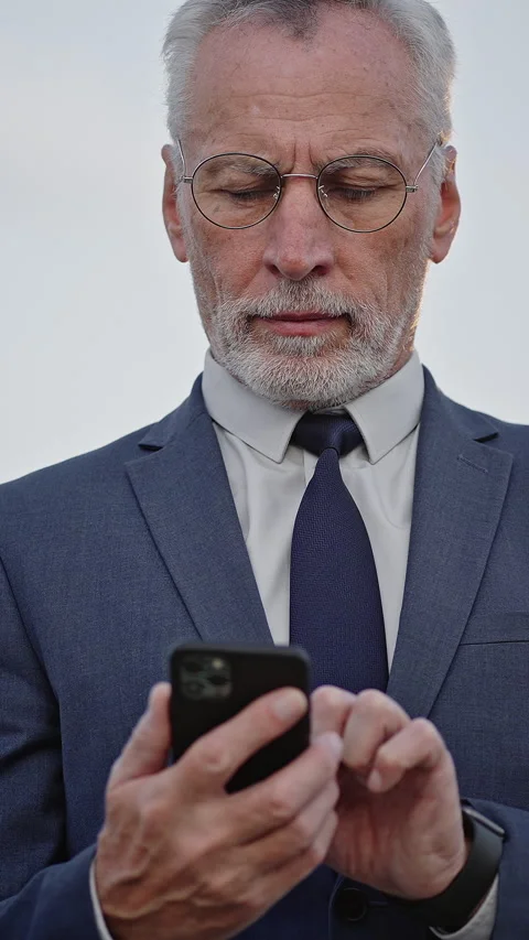 Serious businessman types message to partner on smartphone Stock Footage 329785467