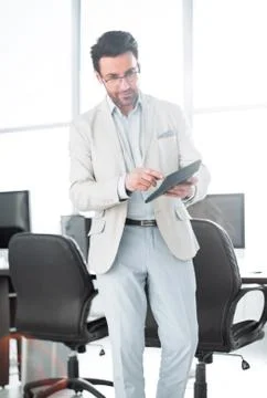 Serious businessman using a calculator while standing in the empty office Stock Photos