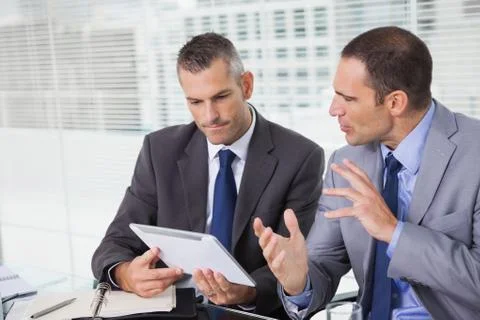 Serious businessmen analyzing documents on their tablet Stock Photos