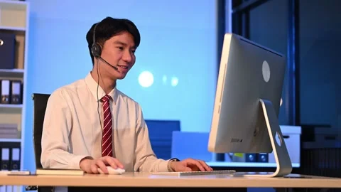 Serious call center operator in wireless headset talking with customer, Asi.. Stock Footage 313578021