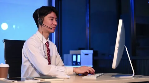 Serious call center operator in wireless headset talking with customer, Asi.. Stock Footage 313578023