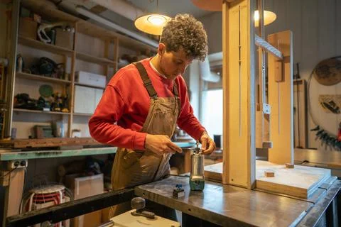 Serious carpenter setting up woodworking machine and vertical drill for upcoming Stock Photos
