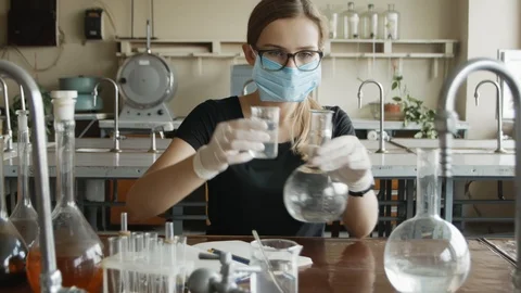 Serious chemist student in mask is doing her research. Portrait young woman i Stock Footage 113347483