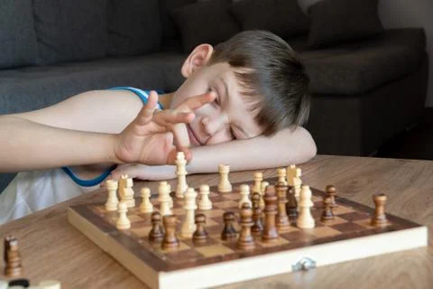 The serious child lost in thought playing chess. Playing board games, on Stock Photos