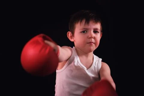 A serious child practices boxing techniques, wearing a white tank and brigh.. Stock Photos