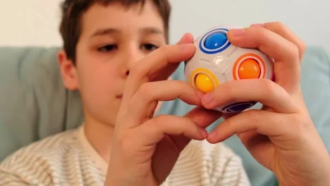 Serious child studies a fidget puzzle sphere in his hands, close up lifestyle Stock Footage 328018400
