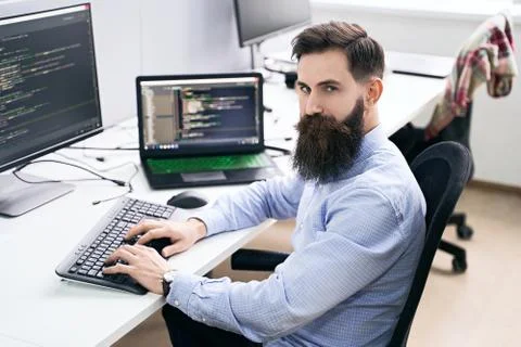 Serious computer programmer developer working in IT office, sitting at desk and 스톡 사진