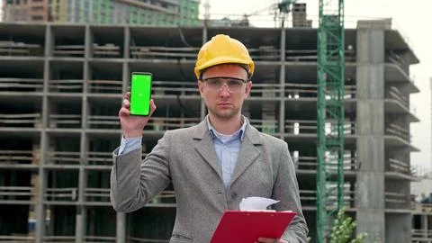 Serious construction inspector posing for camera against unfinished new building Stock Photos