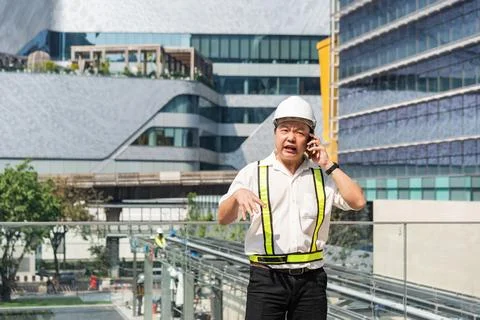 Serious construction supervisor talking on smartphone with worried expressi.. Foto stock