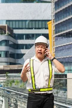 Serious construction supervisor talking on smartphone with worried expressi.. Stock Photos