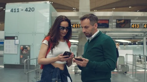 Serious couple checking the time of flight on phone, standing in the hall of Stock Footage 108868839