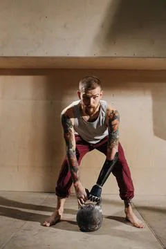 Serious cyborg man with bionic hand training with a kettlebell, doing back ro Stock Photos