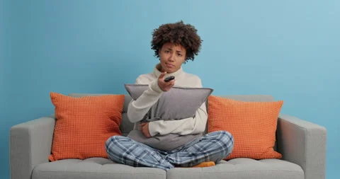 Serious dark skinned holds remote controller and switches channels on smart tv Stock Footage 144065573