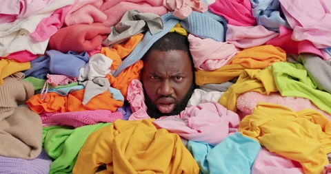 Serious dark skinned man covered in laundry looks around with dissatisfied Stock Footage 156969007