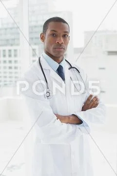 Serious doctor with arms crossed in a medical office Stock Photos