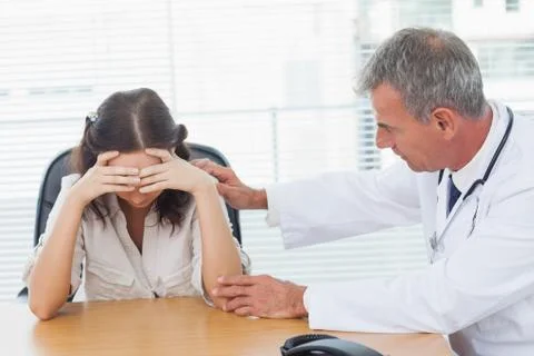Serious doctor comforting his patient after telling her diagnosis Stock Photos