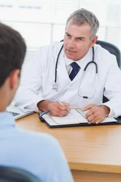 Serious doctor prescribing drug to his patient Stock Photos